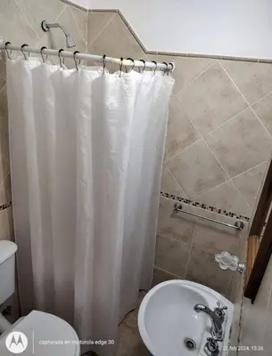 a bathroom with a white shower curtain and a sink at El rincón in Merlo