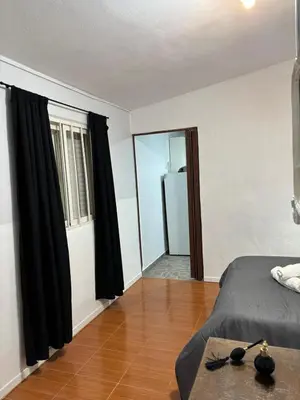 a bedroom with black curtains and a bed and a wooden floor at El rincón in Merlo