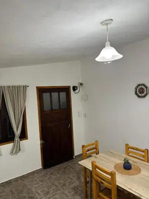 a dining room with a wooden table and a door at El rincón in Merlo