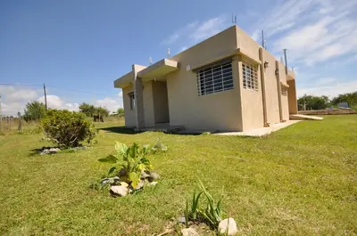 a house in the middle of a grass field at pequeño refugio in Potrero de Garay