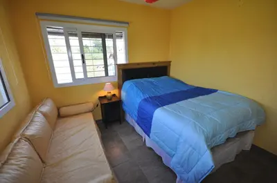 a bedroom with a bed and a couch and a window at pequeño refugio in Potrero de Garay
