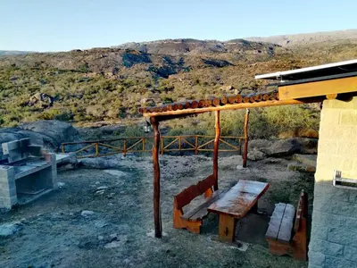 a wooden bench sitting on top of a hill at El Candil de las Altas Cumbres Cabañas Serranas in Nono