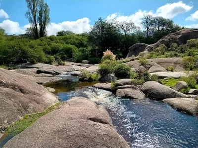a stream of water with rocks and trees at El Candil de las Altas Cumbres Cabañas Serranas in Nono
