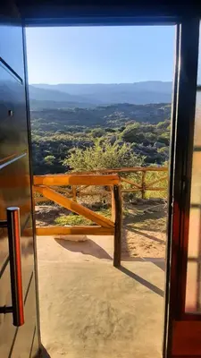a view from a glass door of a view of a valley at El Candil de las Altas Cumbres Cabañas Serranas in Nono
