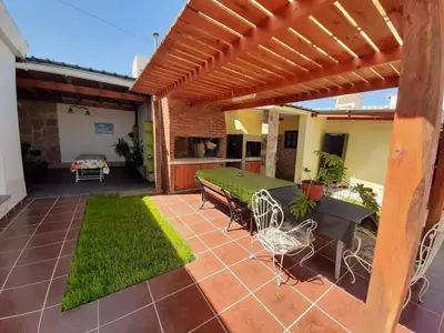 a patio with a wooden pergola and a table and chairs at Departamentos Amanda in Santa Rosa de Calamuchita