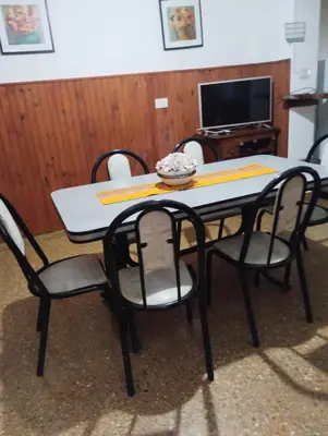 a dining room table with four chairs and a television at Departamentos Amanda in Santa Rosa de Calamuchita
