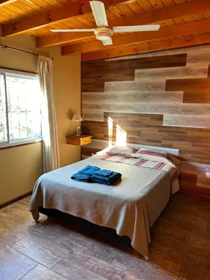 a bedroom with a wooden accent wall and a bed at El Bravo Alojamiento in Villa Rumipal