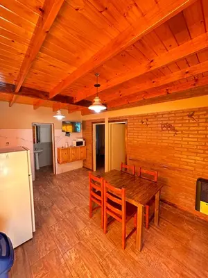 a kitchen and dining room with a wooden table and chairs at El Bravo Alojamiento in Villa Rumipal