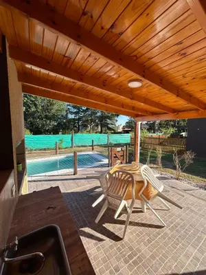 a patio with a table and chairs under a wooden ceiling at El Bravo Alojamiento in Villa Rumipal