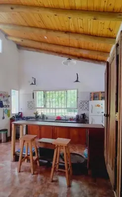 a kitchen with wooden ceilings and a table and two stools at La candelaria in Villa Ciudad Parque