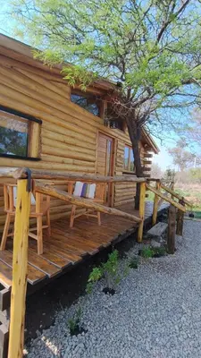 a log cabin with a tree in front of it at Cabaña el atardecer in Villa Anizacate