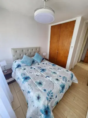 a bedroom with a bed with a blue and white comforter at NUEVEAGUAS - Apartamento Panorámico sobre el Lago in Villa Carlos Paz