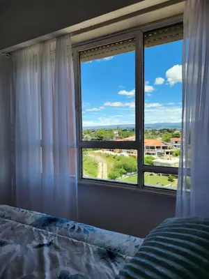 a bedroom with a bed and a large window at NUEVEAGUAS - Apartamento Panorámico sobre el Lago in Villa Carlos Paz