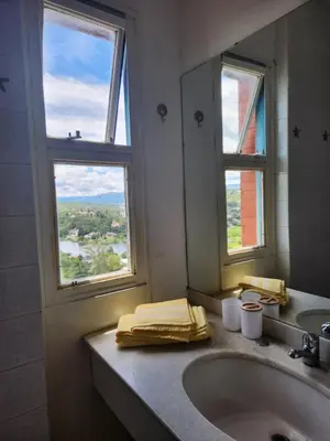a bathroom with a sink and a mirror and two windows at NUEVEAGUAS - Apartamento Panorámico sobre el Lago in Villa Carlos Paz