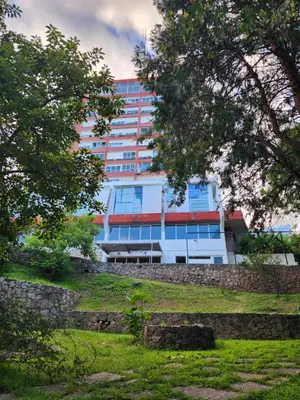 a building in front of a park with trees at NUEVEAGUAS - Apartamento Panorámico sobre el Lago in Villa Carlos Paz