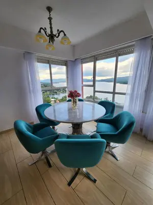 a dining room with a table and blue chairs at NUEVEAGUAS - Apartamento Panorámico sobre el Lago in Villa Carlos Paz