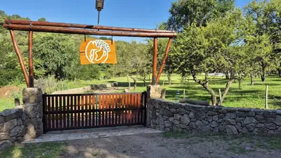 a gate in a stone wall with a sign at Cabañas del Campo - Solo Adultos in Atos Pampa