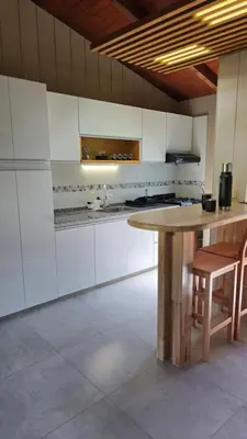 a kitchen with a wooden table and white cabinets at Cabañas del Campo - Solo Adultos in Atos Pampa