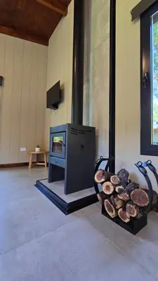 a fireplace with a tv and a pile of logs at Cabañas del Campo - Solo Adultos in Atos Pampa