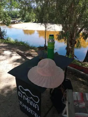 a hat sitting on a table next to a river at El Maná in Villa Cura Brochero