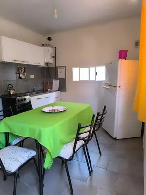 a kitchen with a green table with chairs and a refrigerator at El Maná in Villa Cura Brochero