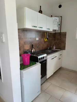 a small kitchen with white cabinets and a stove at El Maná in Villa Cura Brochero