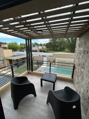 a balcony with two chairs and a table and a pool at Solana Apart in Mina Clavero