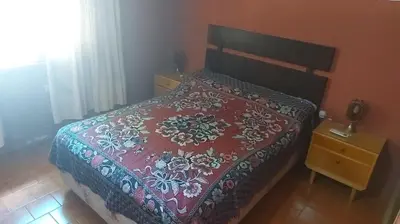 a bedroom with a bed with a red comforter at Casa Pileta Exclusiva A 40 Mtrs Rio Y 2 Minutos Del Centro in Villa Carlos Paz