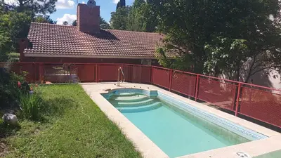 a swimming pool in a yard with a red fence at Casa Pileta Exclusiva A 40 Mtrs Rio Y 2 Minutos Del Centro in Villa Carlos Paz