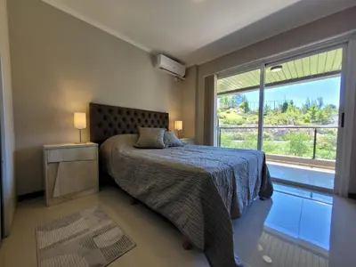 a bedroom with a bed and a large window at Departamento en el lago in Villa Parque Siquiman