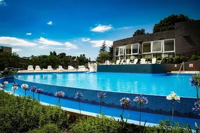 a large swimming pool with chairs and a building at Departamento en el lago in Villa Parque Siquiman