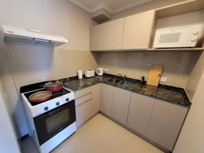a small kitchen with a stove and a microwave at Departamento en el lago in Villa Parque Siquiman