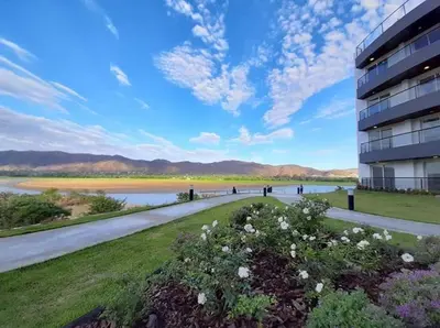 a building with a walkway next to a body of water at Departamento en el lago in Villa Parque Siquiman