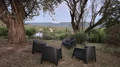 a group of chairs sitting in the grass under a tree at Nautilus in Villa Icho Cruz