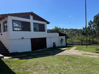 a house with a grass yard in front of it at Casa Lac - Vista al Lago - No se aceptan grupos de jóvenes in Villa Carlos Paz
