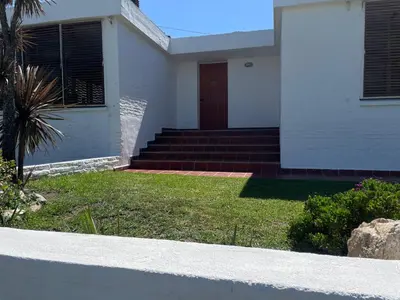 a white house with a red door and stairs at Casa Lac - Vista al Lago - No se aceptan grupos de jóvenes in Villa Carlos Paz
