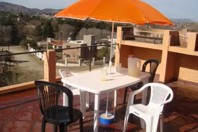 a table and chairs with an orange umbrella on a balcony at Cerritos Departamento in Villa Carlos Paz