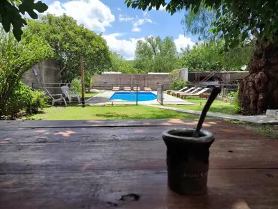 a cup with a straw sitting on a table with a pool at Residencial Buenos Aires in Mina Clavero