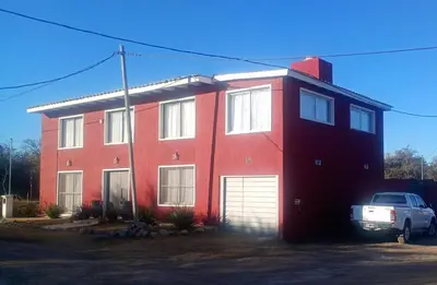 a red house with a car parked in front of it at Las Brisas - Hospedaje Serrano in Santa María