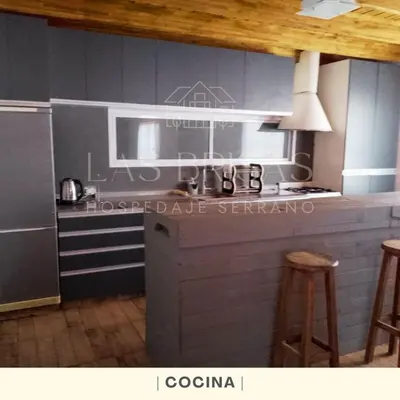 a kitchen with a stove and a counter with stools at Las Brisas - Hospedaje Serrano in Santa María