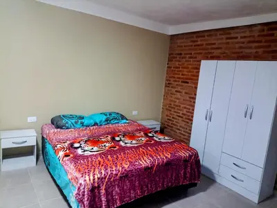a bedroom with a bed and a brick wall at Atardecer Serrano in Nono