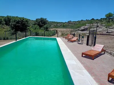 a swimming pool with wooden chairs and a group at Atardecer Serrano in Nono