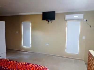a bedroom with a bed and a tv on the wall at Atardecer Serrano in Nono