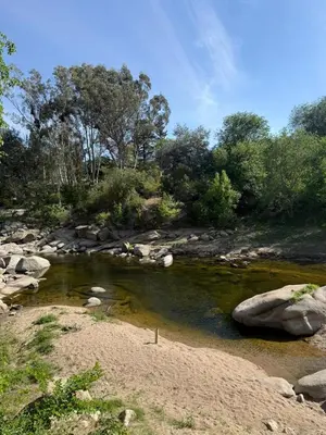 a river with rocks and trees in the background at Cabaña frente al balneario diquecito solo familias in Villa Carlos Paz