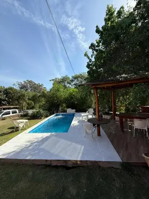 a swimming pool with chairs and a gazebo at Cabaña frente al balneario diquecito solo familias in Villa Carlos Paz