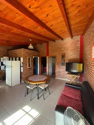 a living room with a couch and a table and a refrigerator at Cabaña frente al balneario diquecito solo familias in Villa Carlos Paz