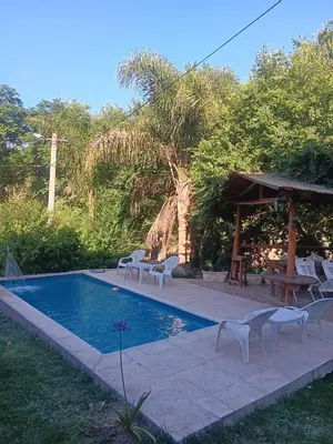 a pool with chairs and a table and a pavilion at Cabaña frente al balneario diquecito solo familias in Villa Carlos Paz