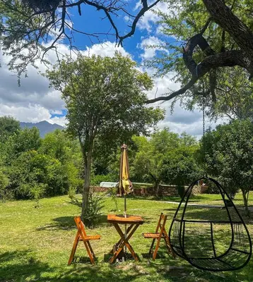 a picnic table with an umbrella and a swing at Puesto de Montaña - Casa con pileta privada in Los Hornillos