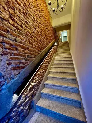 a staircase with a brick wall and a chandelier at Tu Lugar en Cordoba in Cordoba