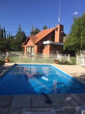 a blue swimming pool in front of a house at Cabaña Los Estribos 1 in Merlo